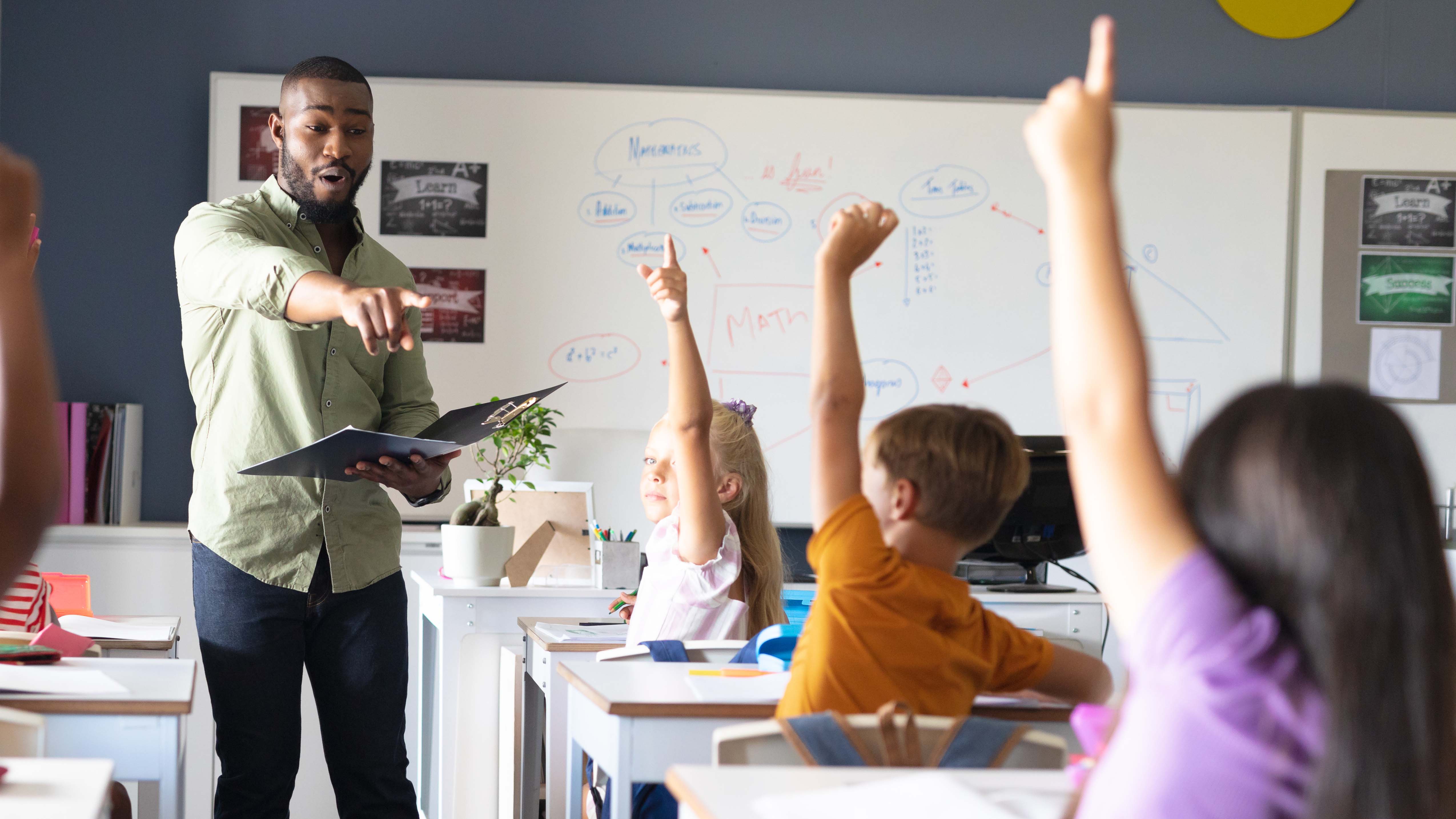 Teacher in classroom picking student to answer question