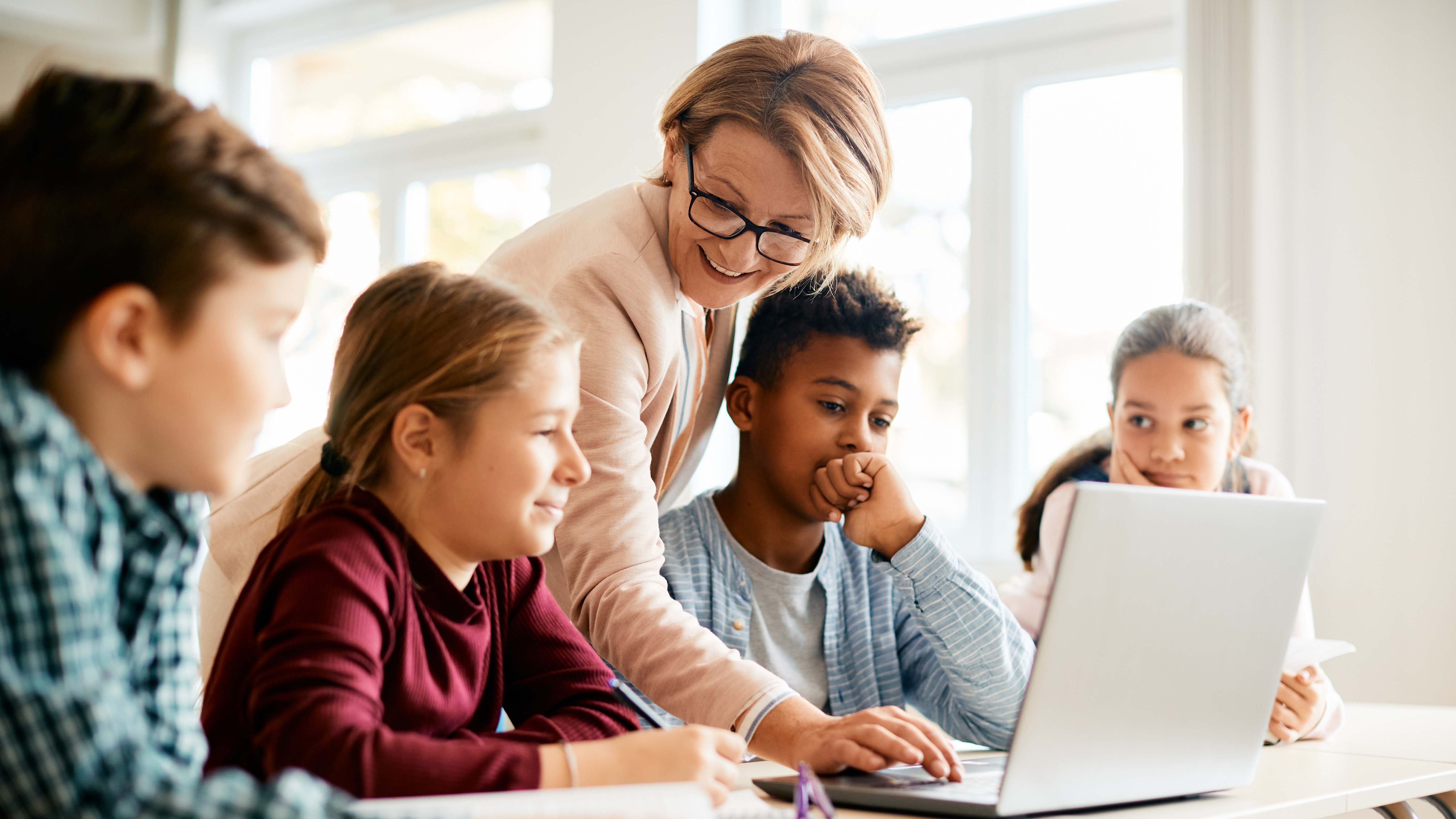 Teacher and student in elementary setting using laptop during computer class