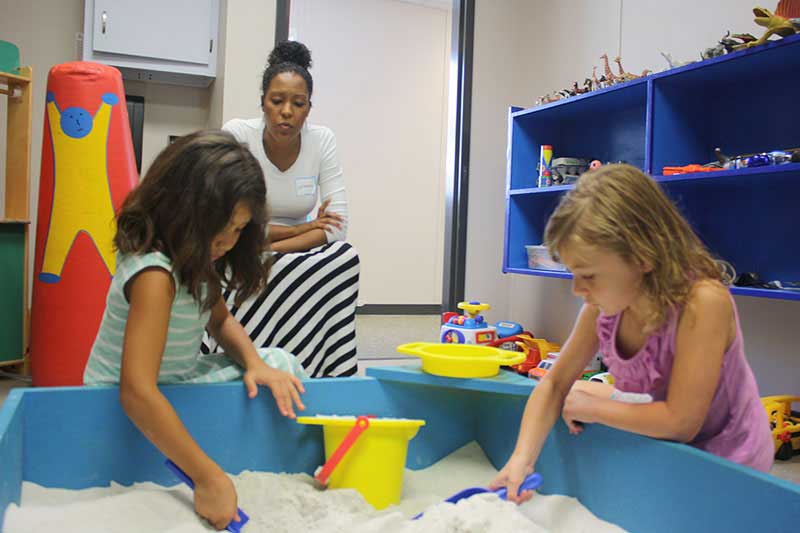 Teacher playing with student in a sandbox