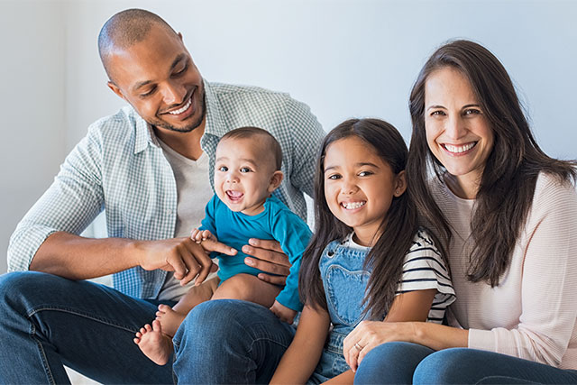 Smiling family sits on a couch