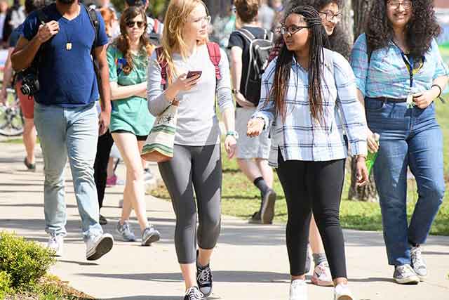 Students talk while walking across the University of North Texas campus on a sunny day.