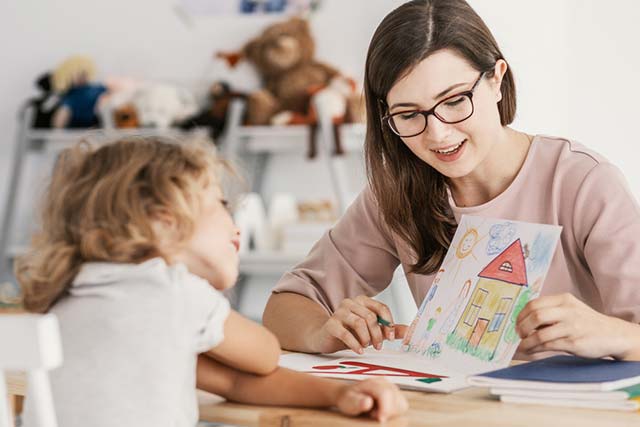 A teacher meeting with a child and looking at artwork.