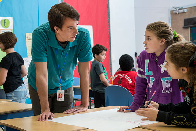 A UNT student teacher talks to middle school students in a classroom