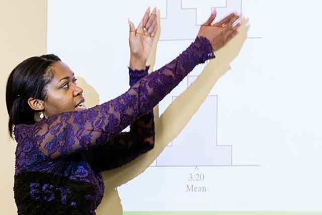 A UNT graduate student points to graphs displayed by a project as she explains their meanings.