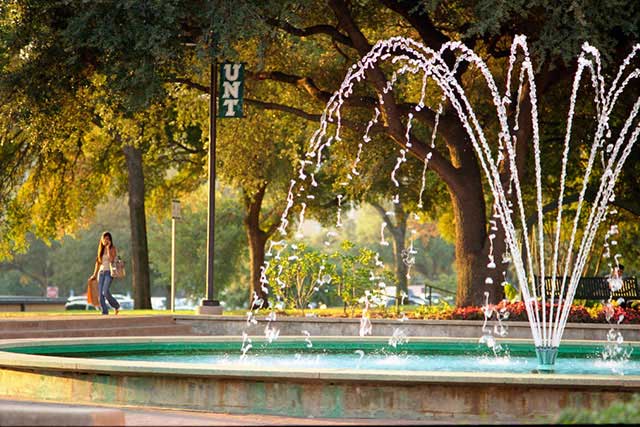  UNT students walk past a fountain