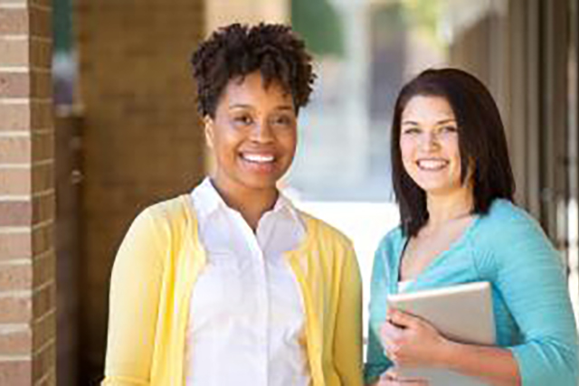 Two teachers smiling at a camera