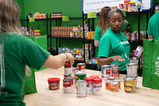 Students pack canned goods in green grocery bags at the UNT Food Pantry.
