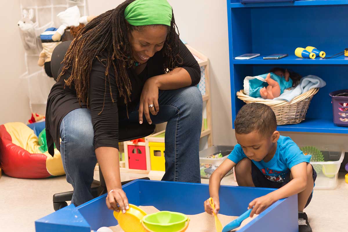 Dr. Natalya Lindo plays in the sand with a child at the UNT Center for Play Therapy.