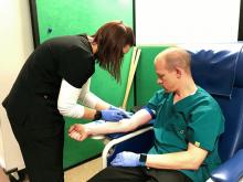 A graduate student draws blood from Dr. Brian McFarlin
