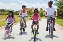 A family rides bicycles through a neighborhood.