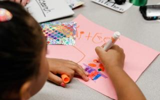 A child uses markers to draw on construction paper.